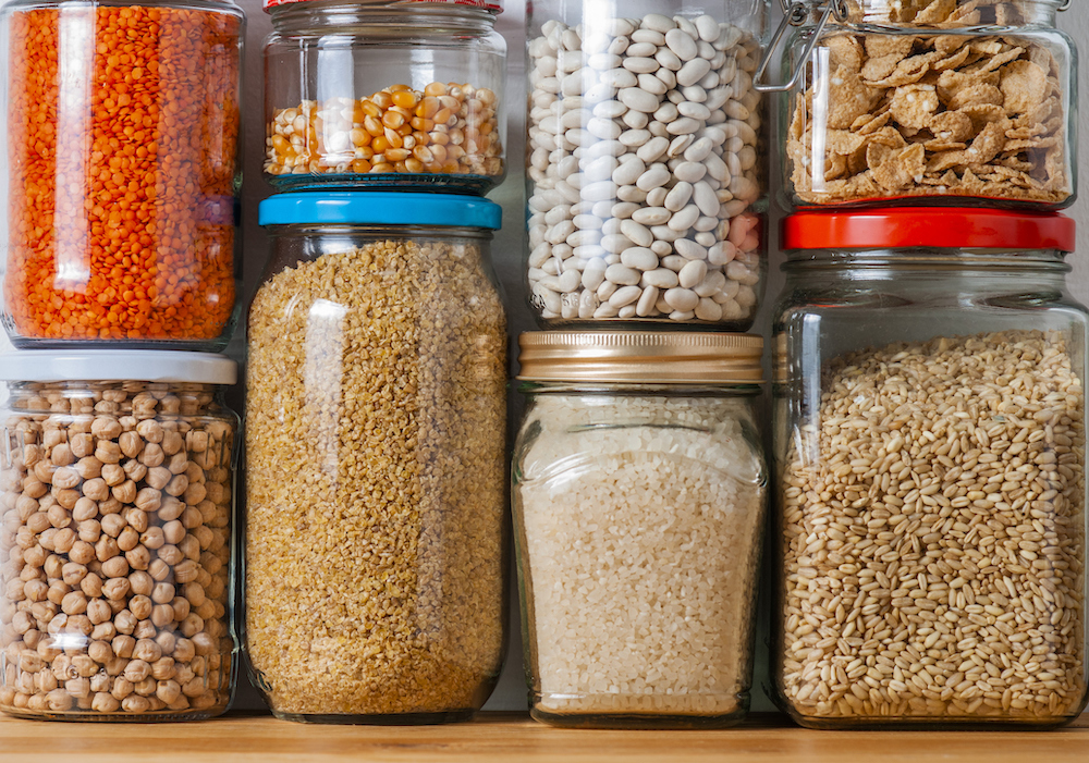 Jars containing dried goods stacked in a pantry.