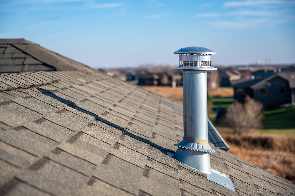 Silver vent pipe on roof of home on a sunny day.