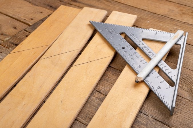 Drawing a line in a carpentry shop using a speed square.