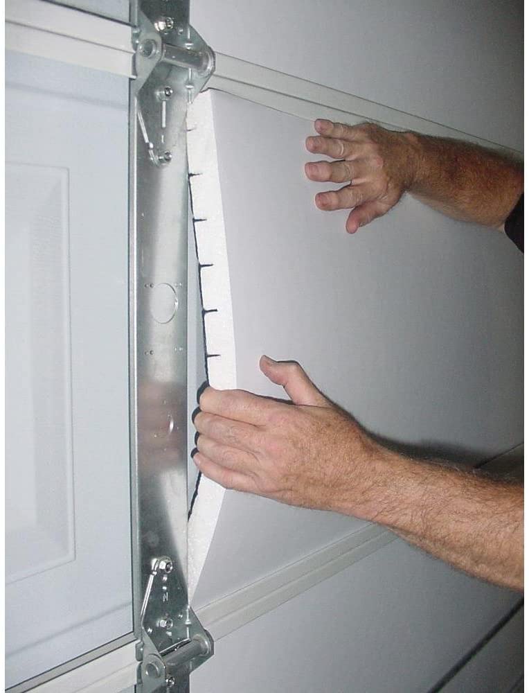 Man pushes rigid foam insulation panels into the back of a garage door.