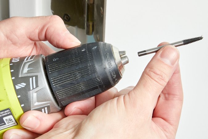 Woman inserts a screw extractor into a drill.