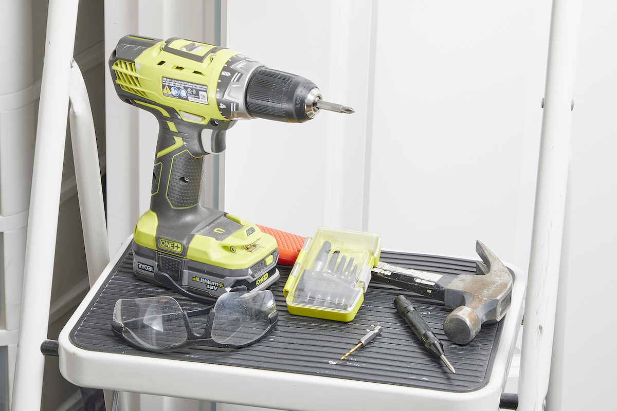 Drill, hammer, and screw extractor on a step stool.