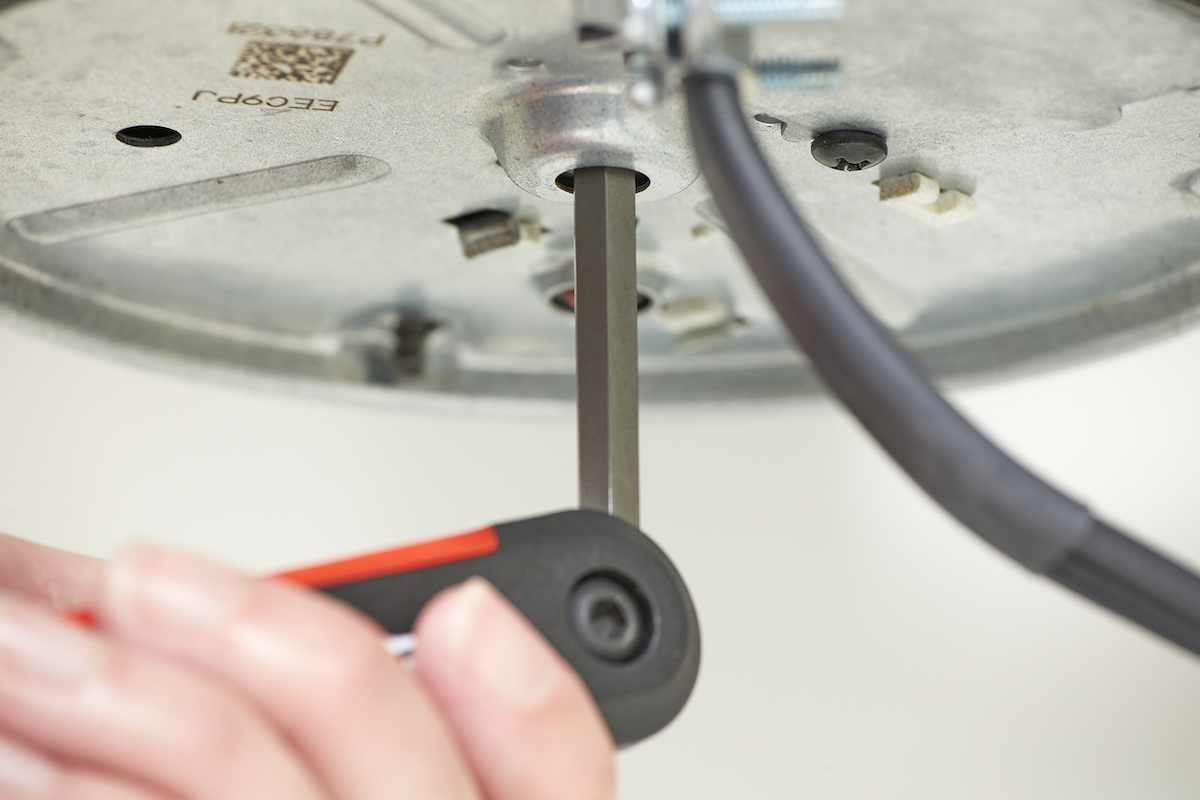 Woman inserts a hex key into the bottom of a garbage disposal.