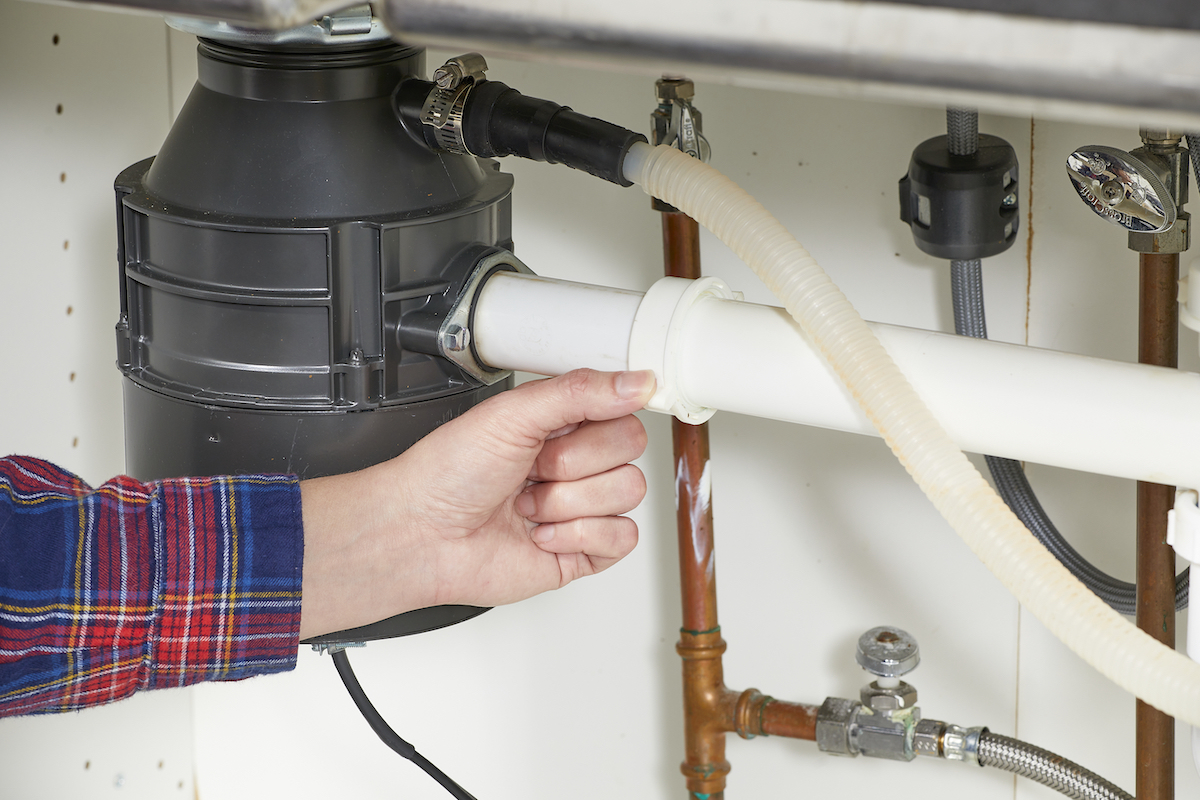 Woman checks the pipe that leads into the garbage disposal for leaks.