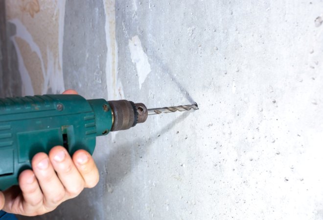 A close up of a drill being used to drill into concrete.