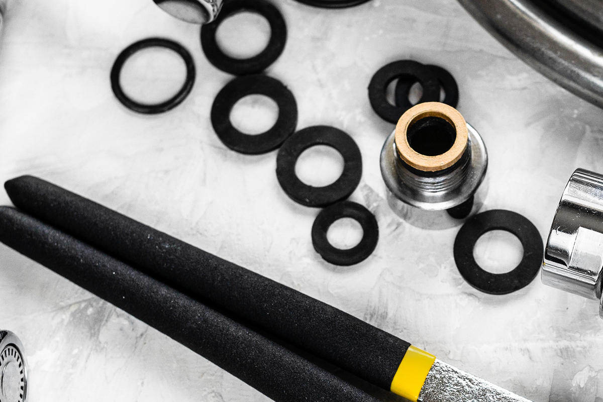 Black rubber o-rings are scattered above a black and metal wrench and shower parts.