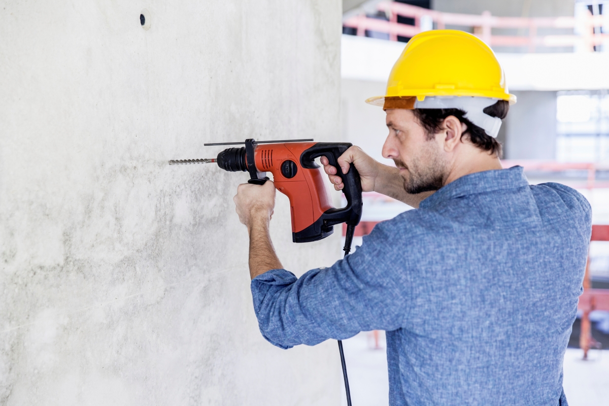 A professional contractor is using a tool to drill into a concrete wall.