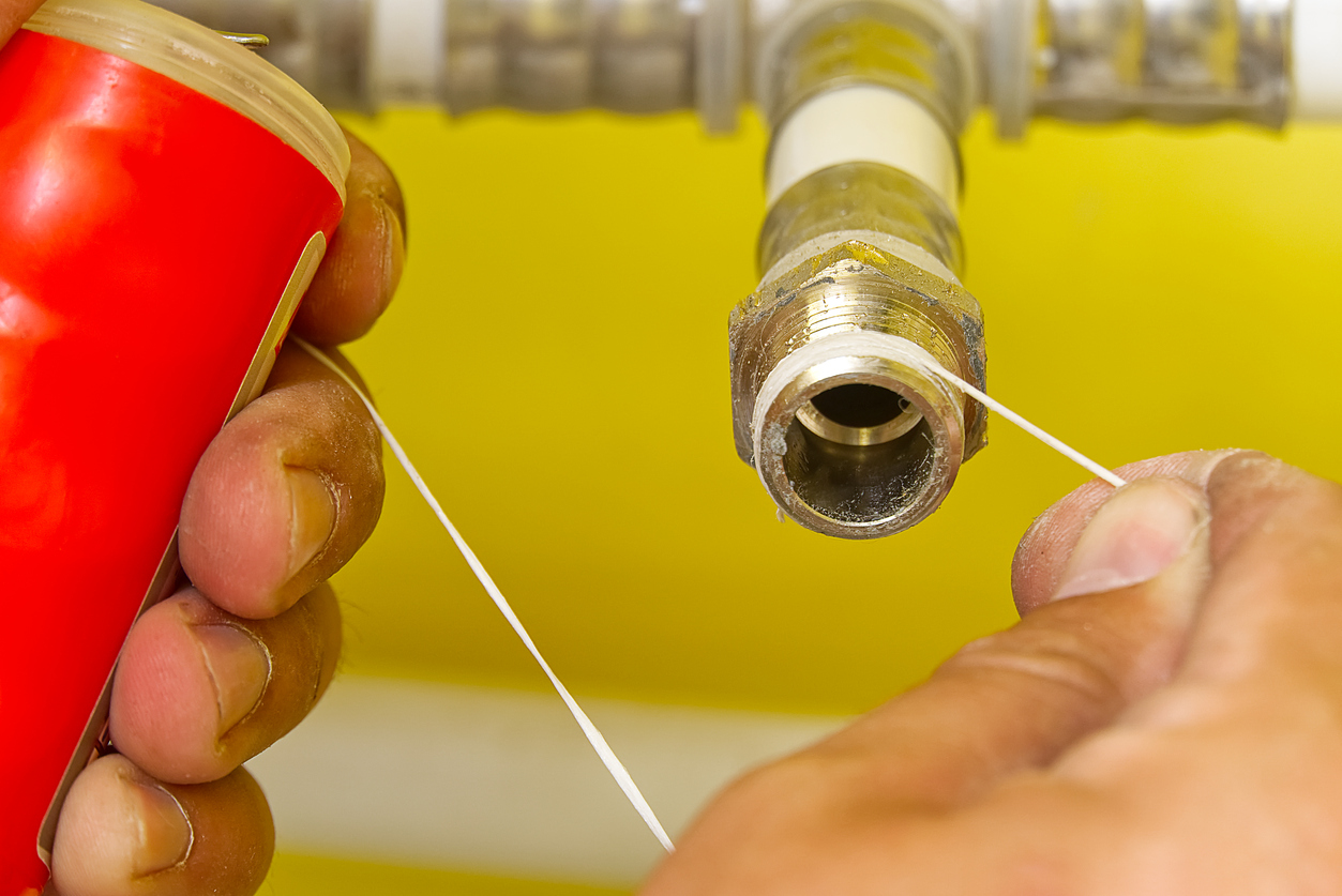 A person is wrapping teflon tape around a shower arm.