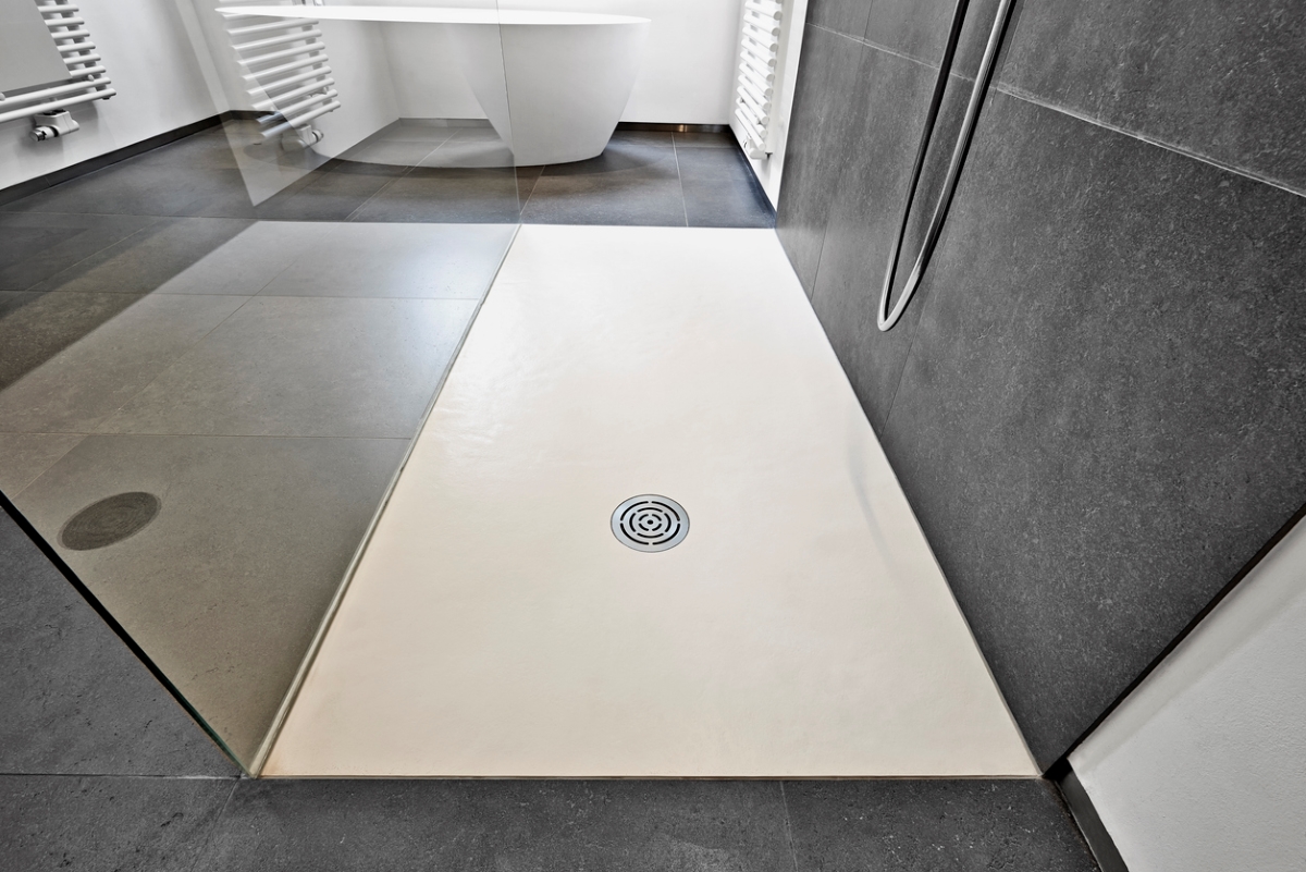 A close look of the white shower pan in walk-in modern shower.