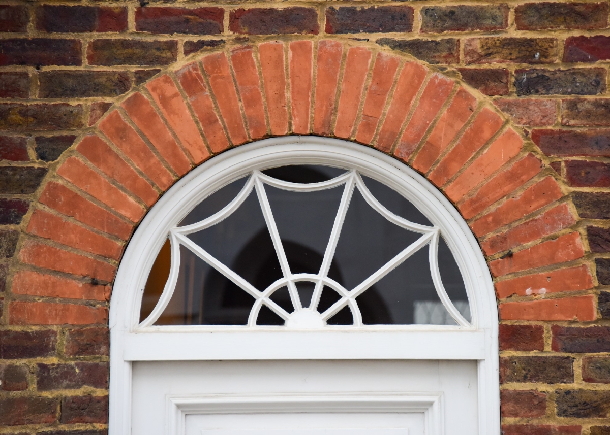 Circular transom window above the doorway surrounded by brick.