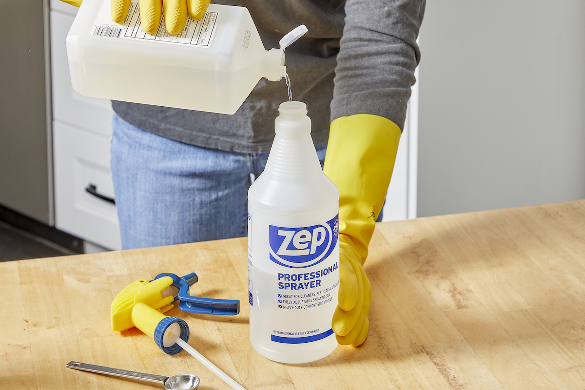 Woman pours isopropyl alcohol into a spray bottle.