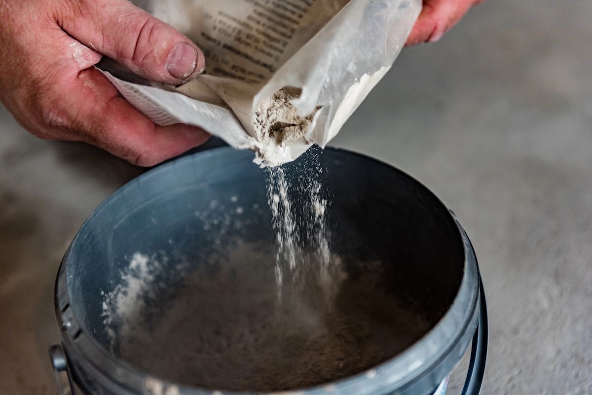 Worker's hands mixing grout for filling space between ceramic tiles.