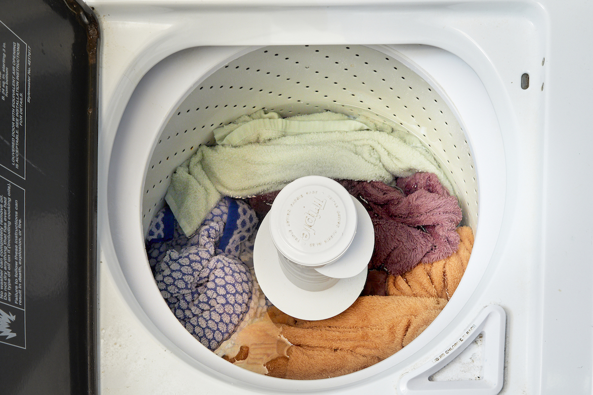 Bird's eye view looking down into a top-load washer full of laundry.