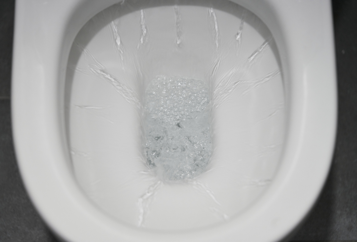 A toilet bowl is flushing water down the drain.