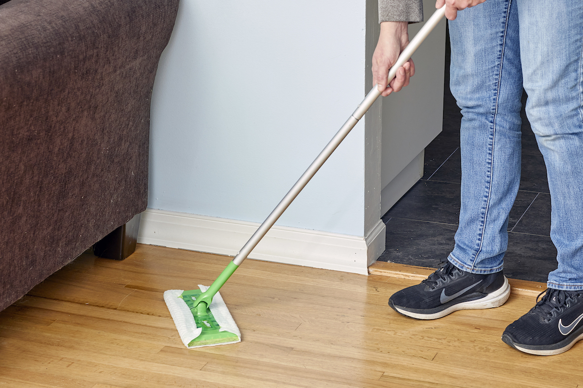 Woman uses a Swiffer mop to dry mop a hardwood floor.