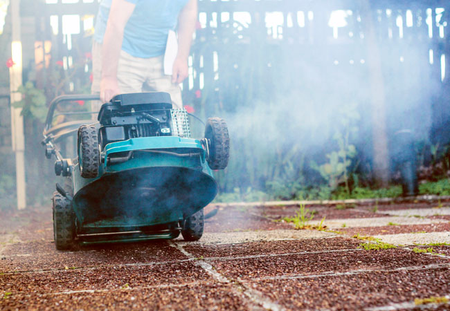 A lawn mower with smoke billowing from it.