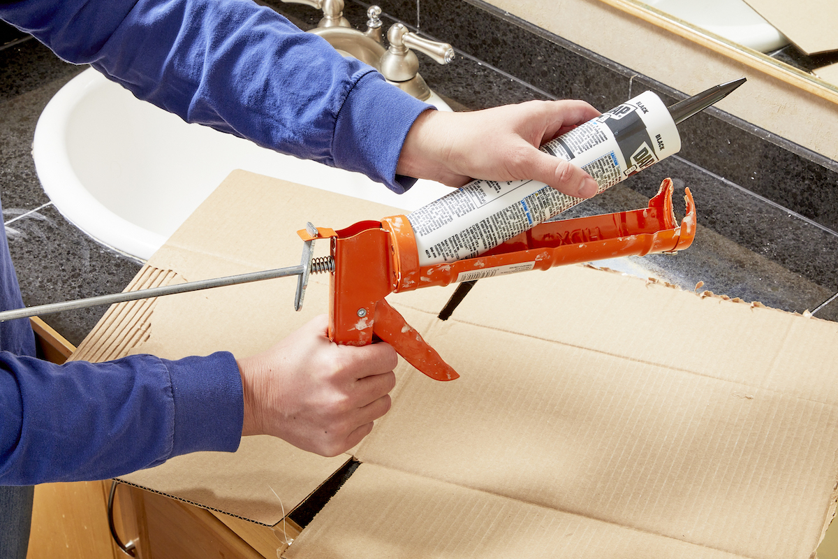 Woman loads a tube of caulk into a caulk gun.