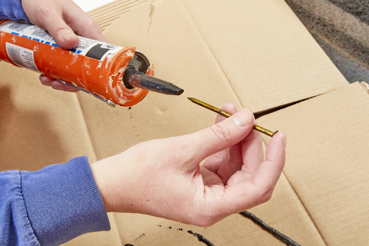 Using a nail to open the seal on the caulk.