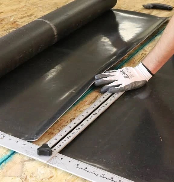 Person measures mass loaded vinyl with a yardstick.