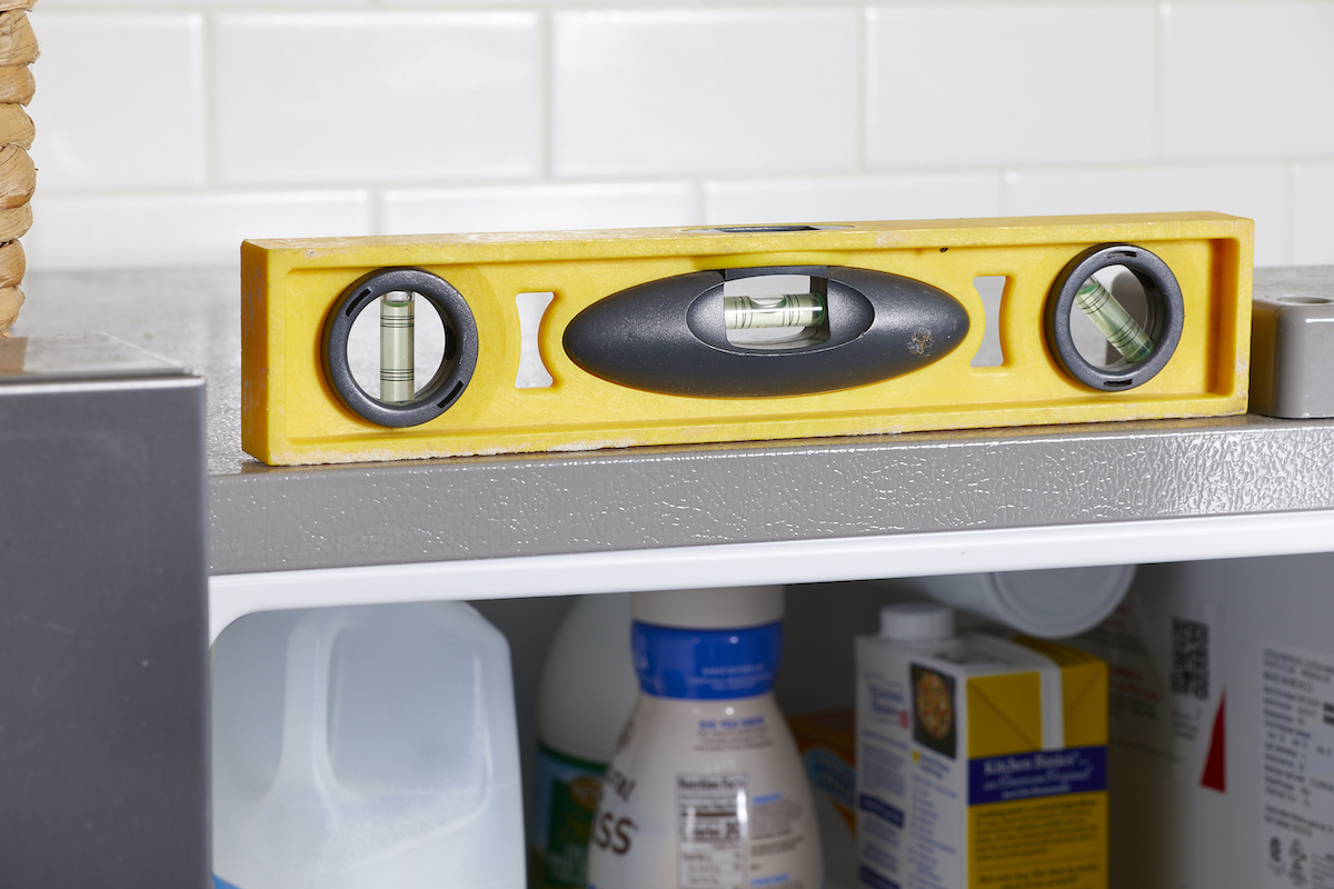 A yellow level sitting on top of an open refrigerator.