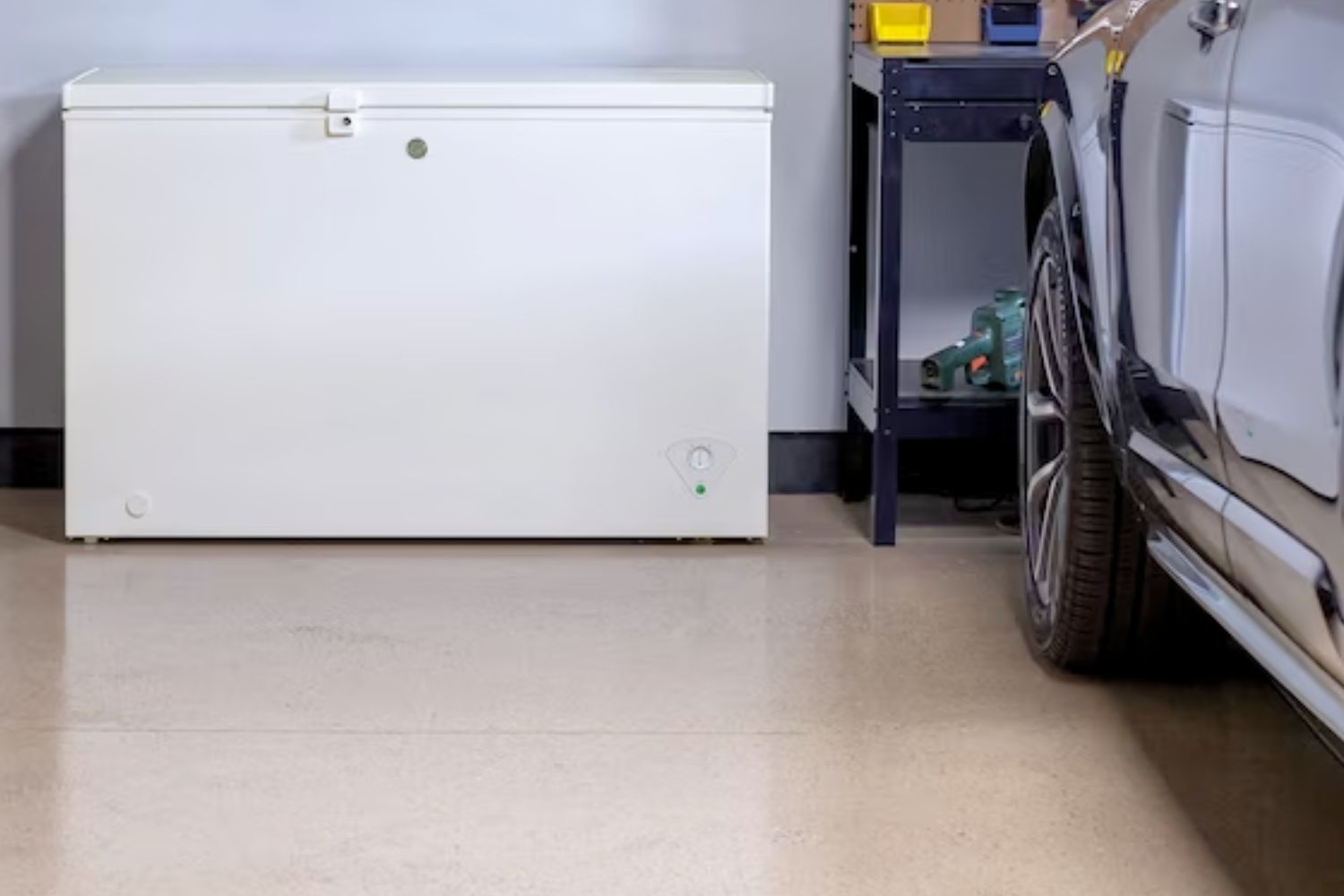 The best chest freezer in a garage next to a storage rack and parked car.