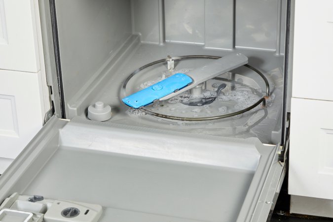 An open dishwasher, with water filling the bottom of the appliance.