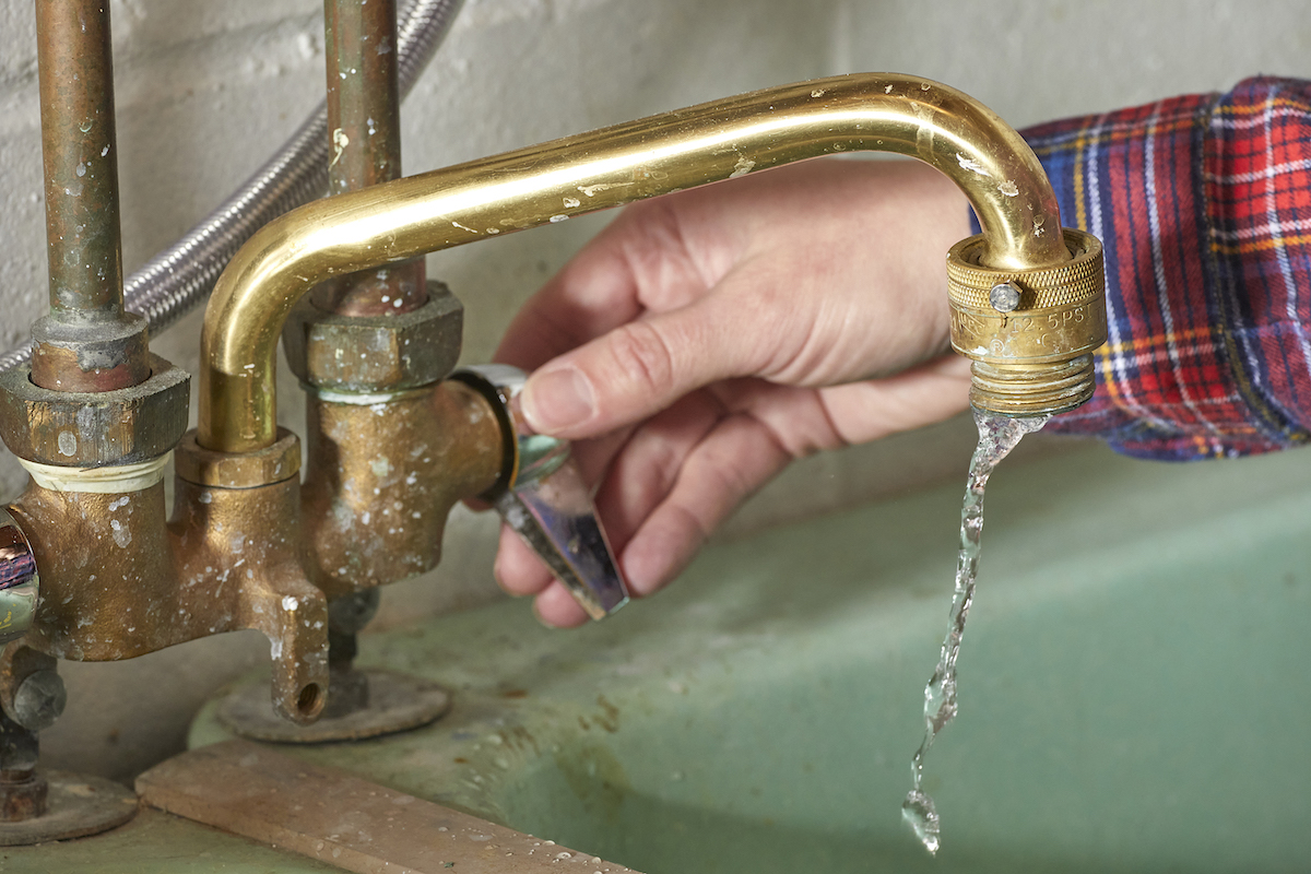 Woman opens tap on laundry sink faucet.