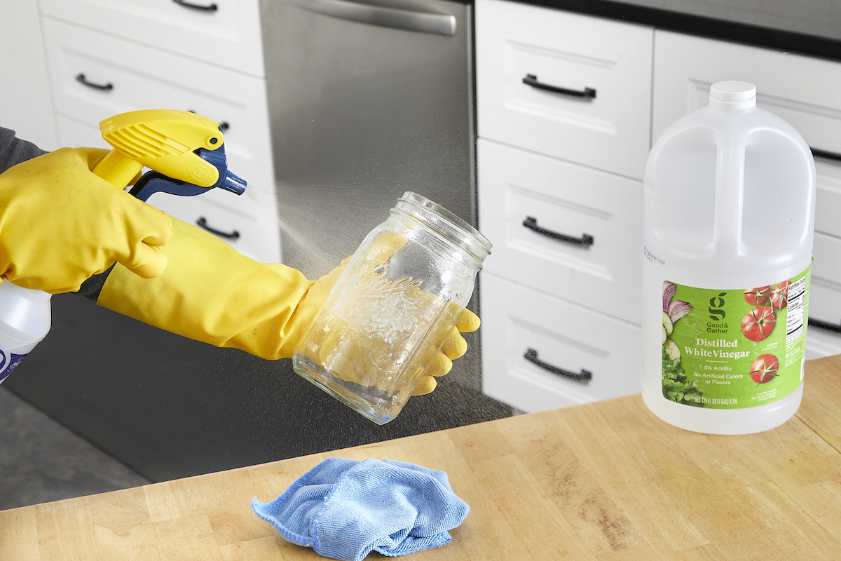 Woman sprays vinegar on a mason jar.