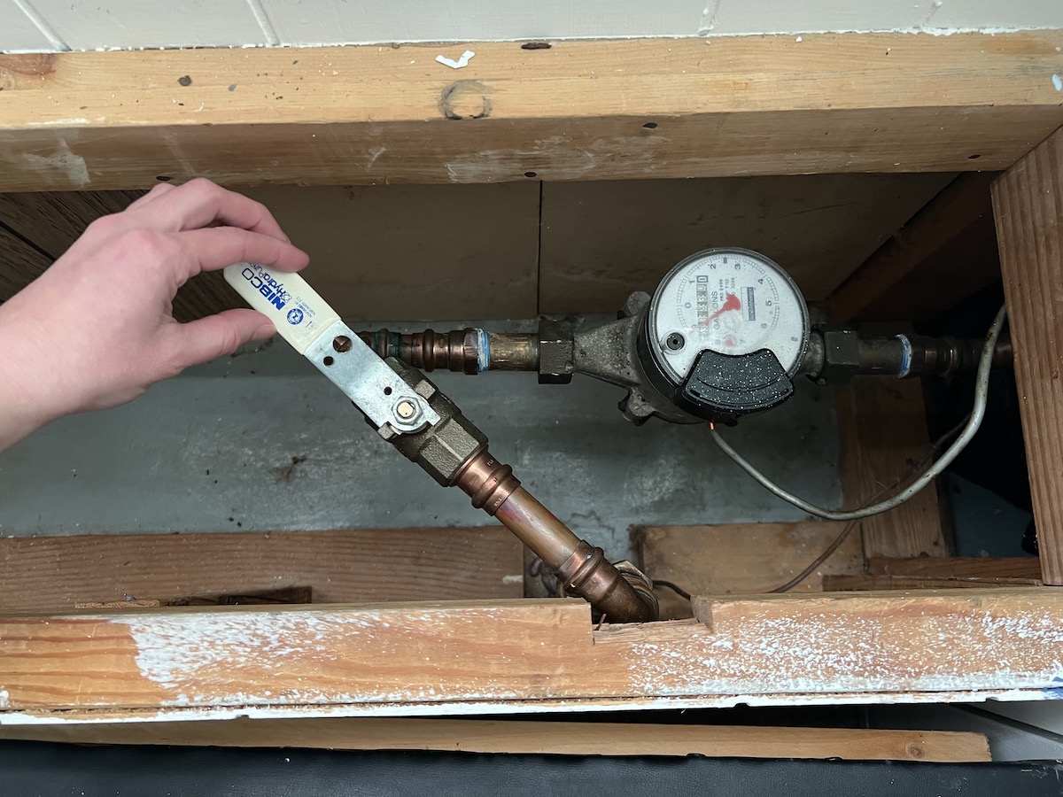 Woman opens her home's water shutoff valve.