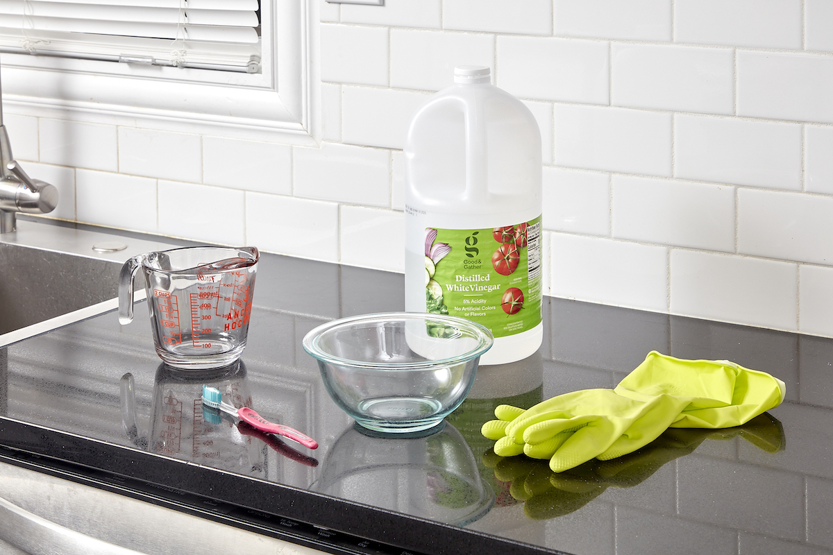 Materials needed to clean a dishwasher laid out on a kitchen countertop.