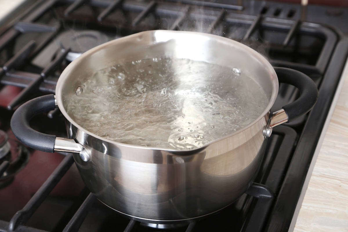 Water is boiling inside of a metal saucepan on a stove.