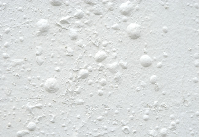 A white wall with bubbling paint.