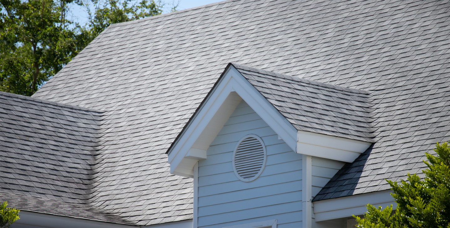 garret house and Roof shingles on top of the house among a lot of trees. dark asphalt tiles on the roof background