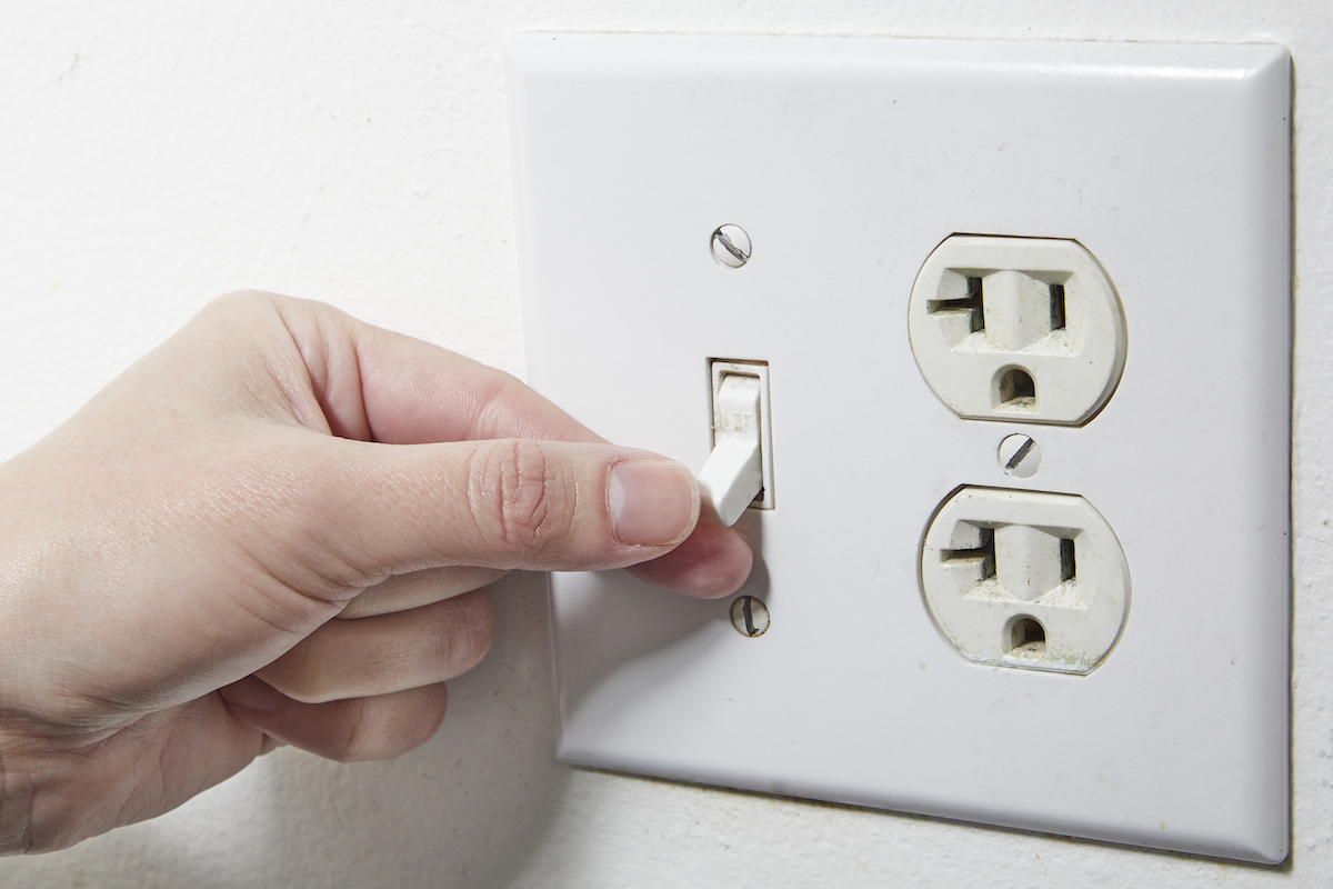 Woman flips the switch on a half-hot outlet.