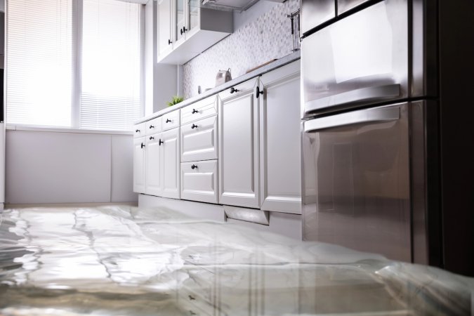 Kitchen with white cabinets and stainless refrigerator with wet floor.