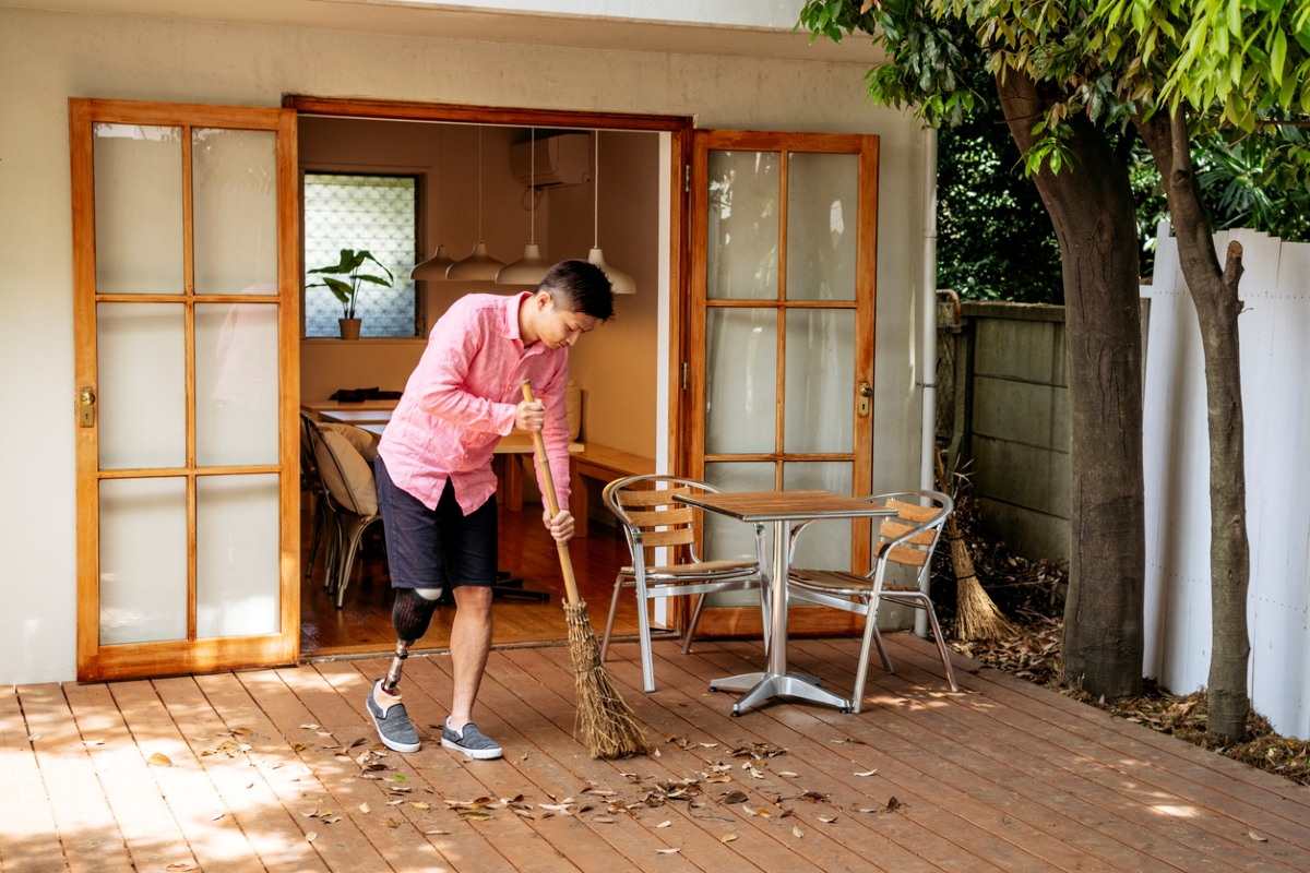 Man sweeping a wood deck with a broom.