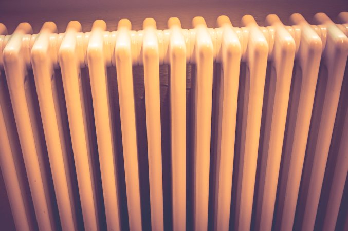 Close up image of a retro radiator with fins in dappled sunlight.