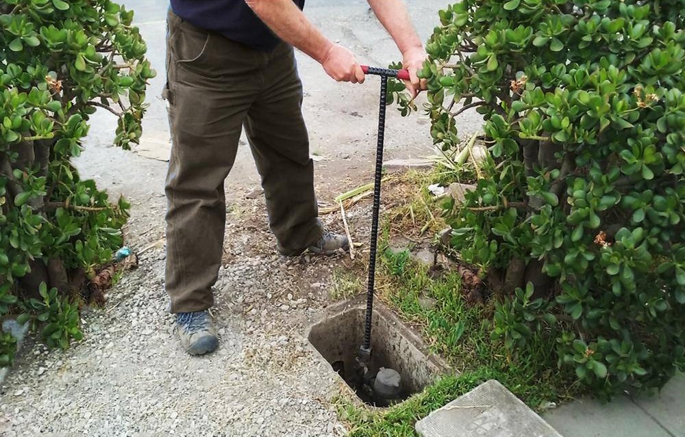 Man using a water key to access the water lines outside his home.