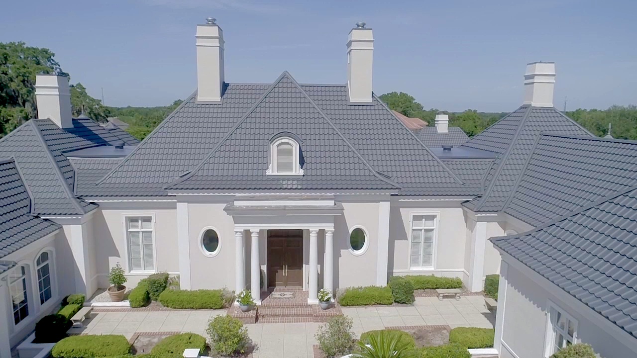 A large luxury home has grey shingles on the roof.