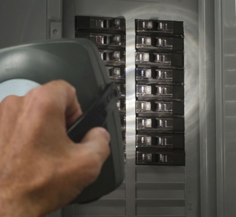 A close up of a hand fixing a breaker box.