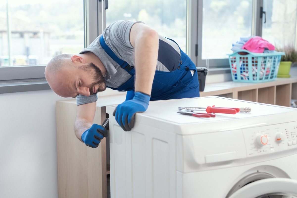 Repairman fixing back of dryer.