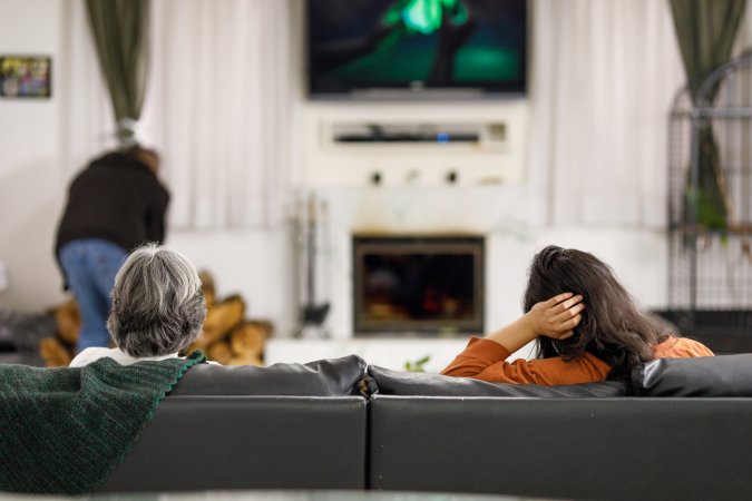 tv above fireplace woman watching tv with elderly parents in living room with tv mounted above fireplace