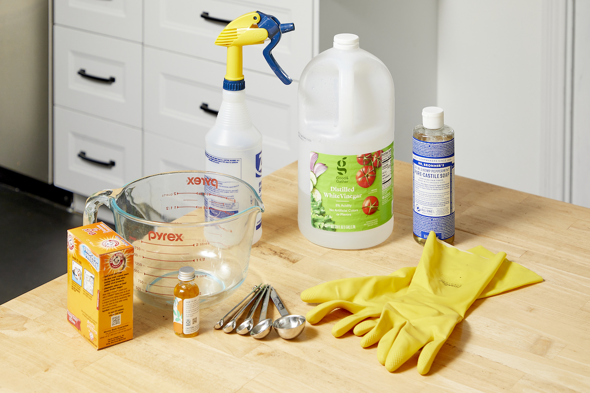 Ingredients needed to make a homemade degreaser (including vinegar and baking soda) assembled on a counter.