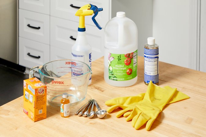 Ingredients needed to make a homemade degreaser (including vinegar and baking soda) assembled on a counter.