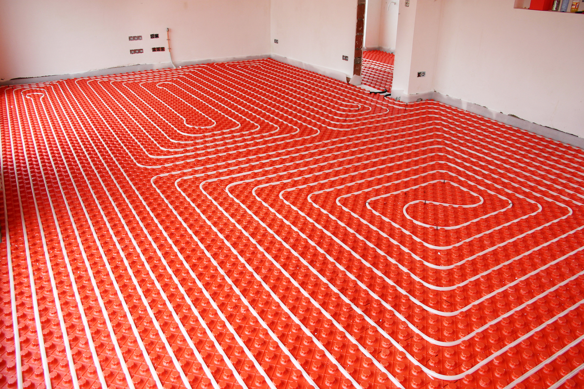 Radiant floor heating system with a red base and paths of piping over top.