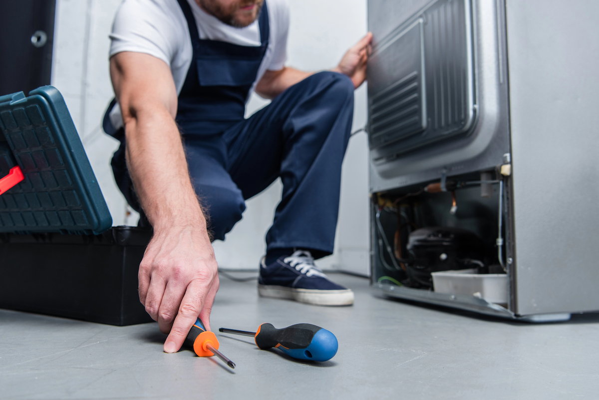 Technician making repairs in the rear of the refrigerator.