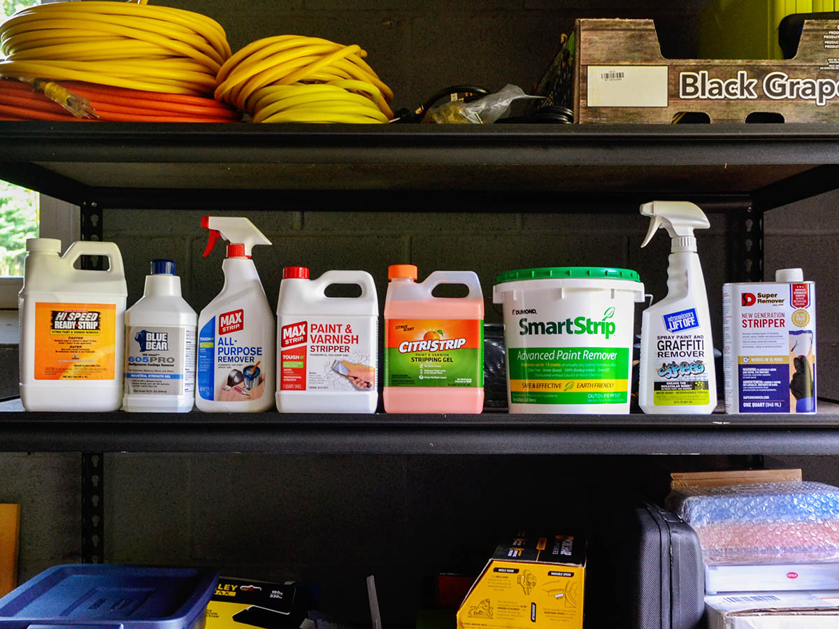 Several paint strippers lined up on a garage shelf