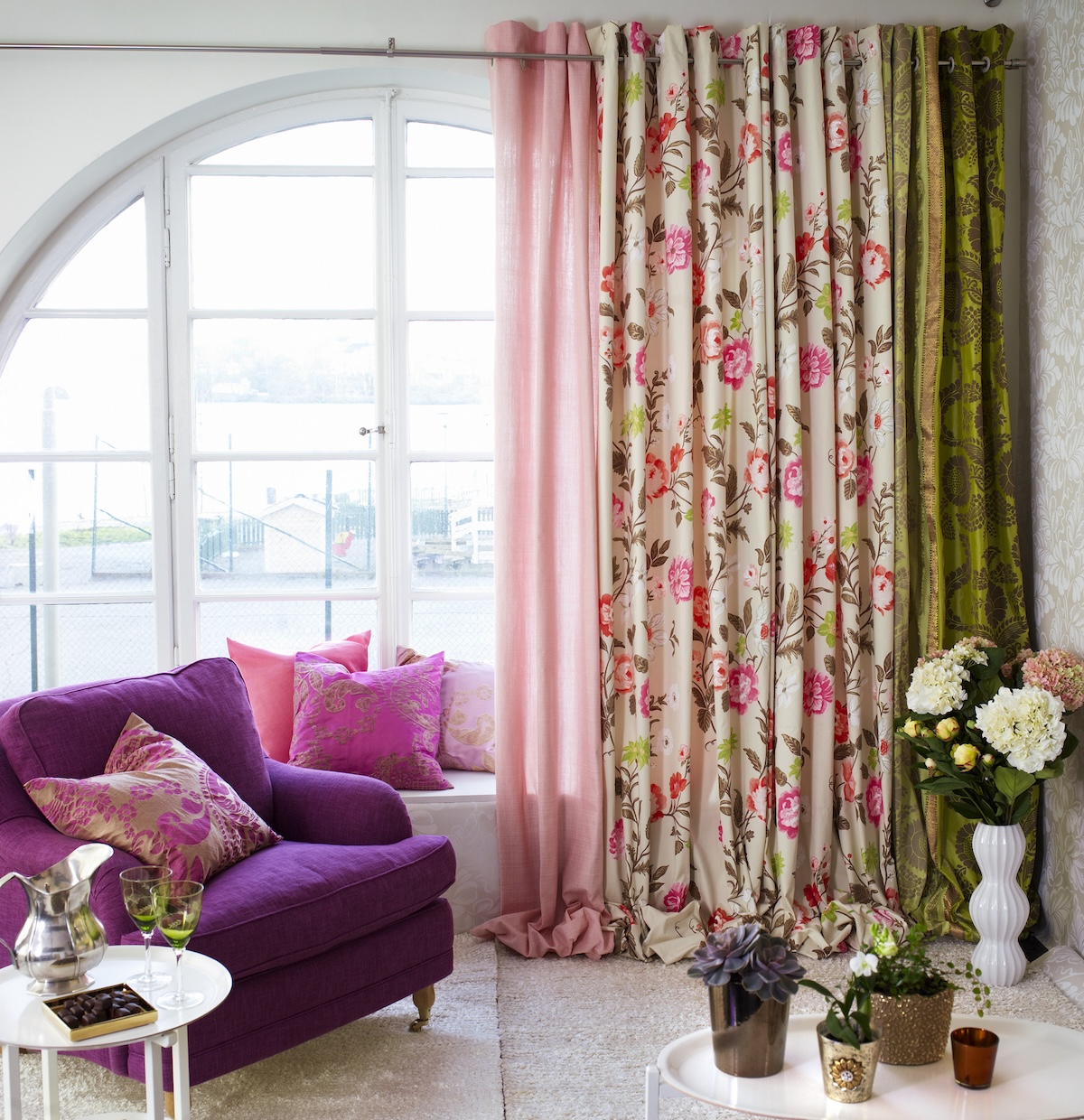 Bright curtains with a combination of pink, green, and cream-colored designs hang in a chic living room.