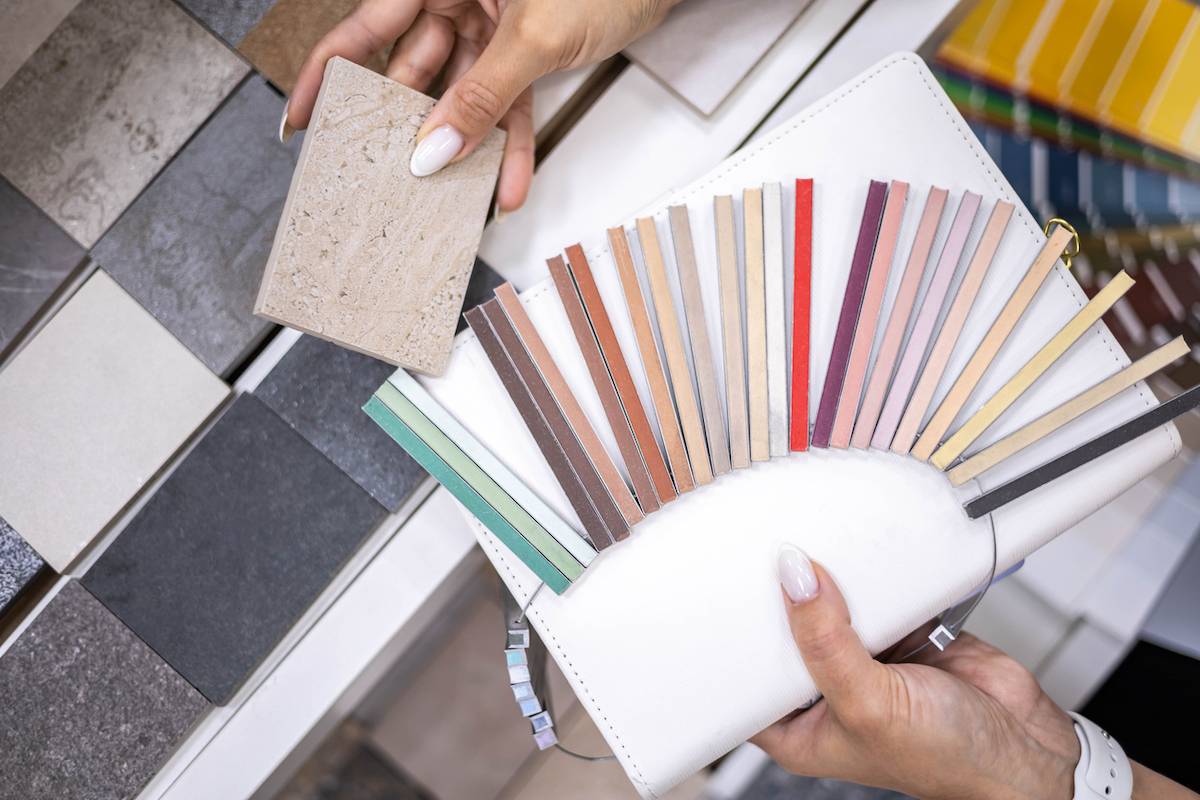 Female interior designer holding samples of grout next to a tile.