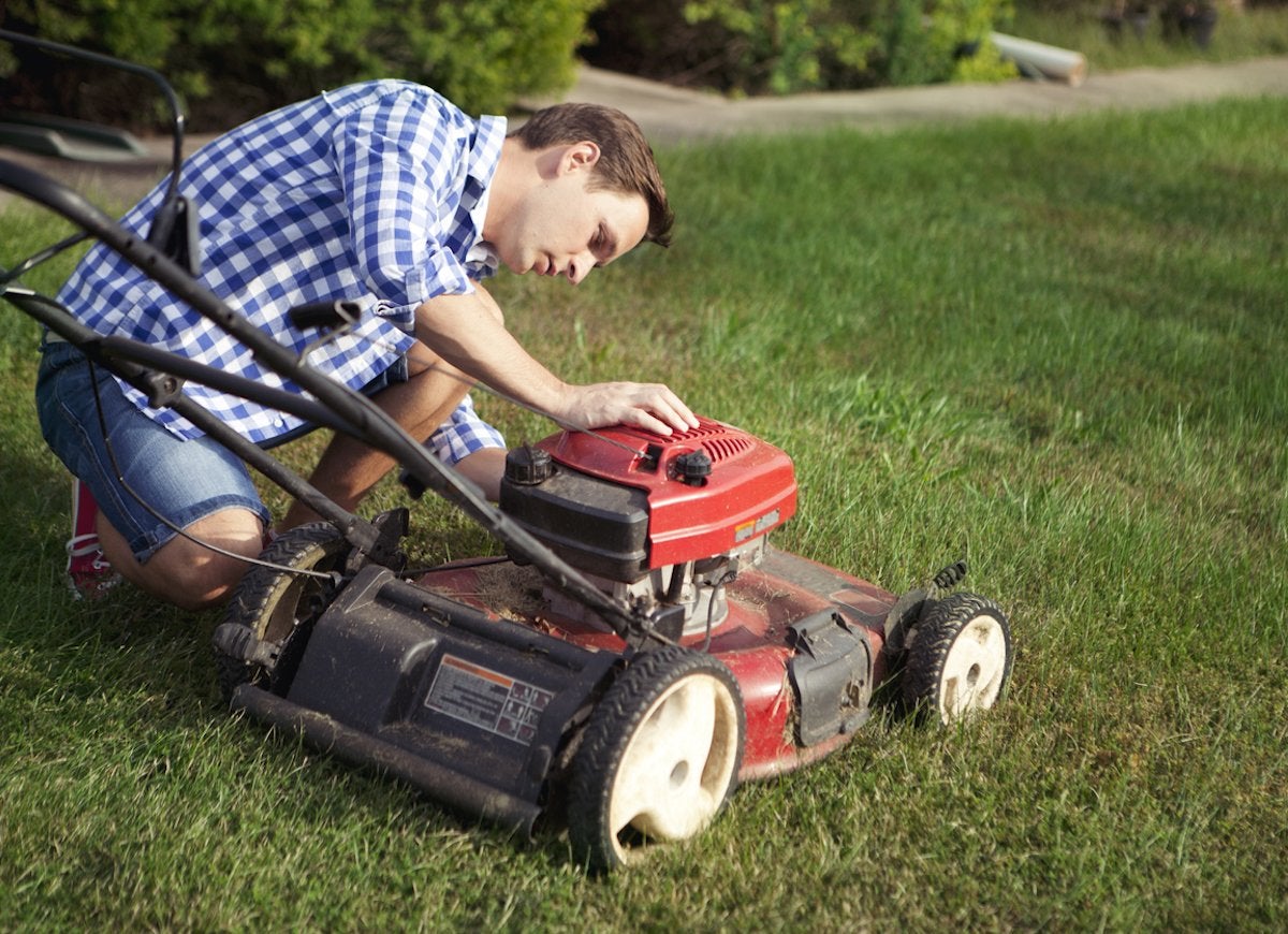 A man looking at his lawn mower.